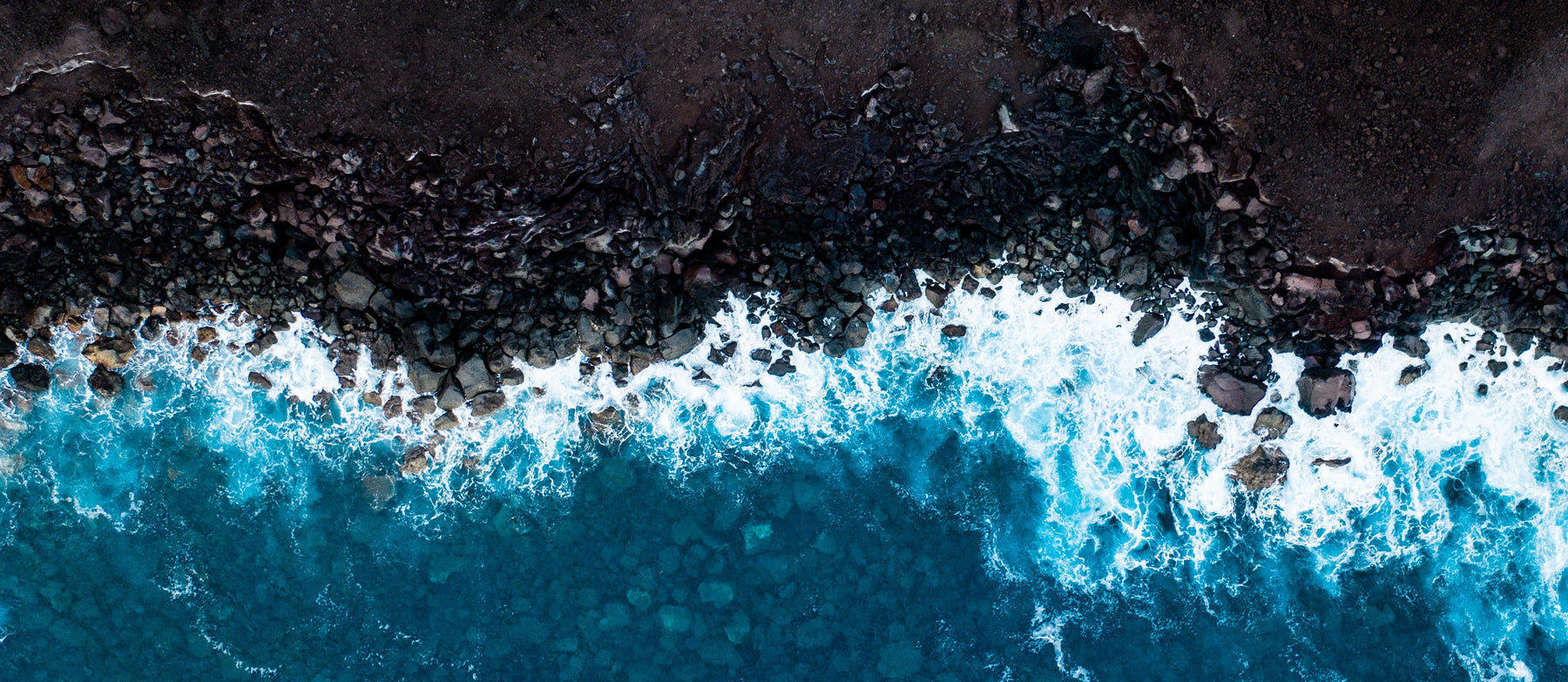 photo aérienne d'une eau se brisant sur un rivage sombre