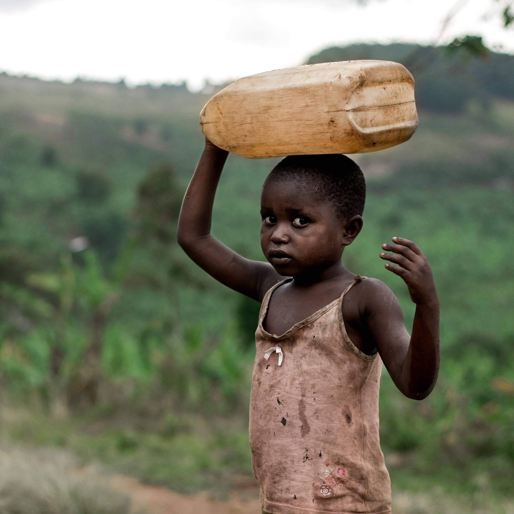 un enfant qui marche avec un jerrican d'eau en équilibre sur sa tête