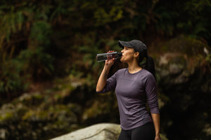 Une femme en randonnée buvant dans une bouteille d'eau en Tritan de Santevia.
