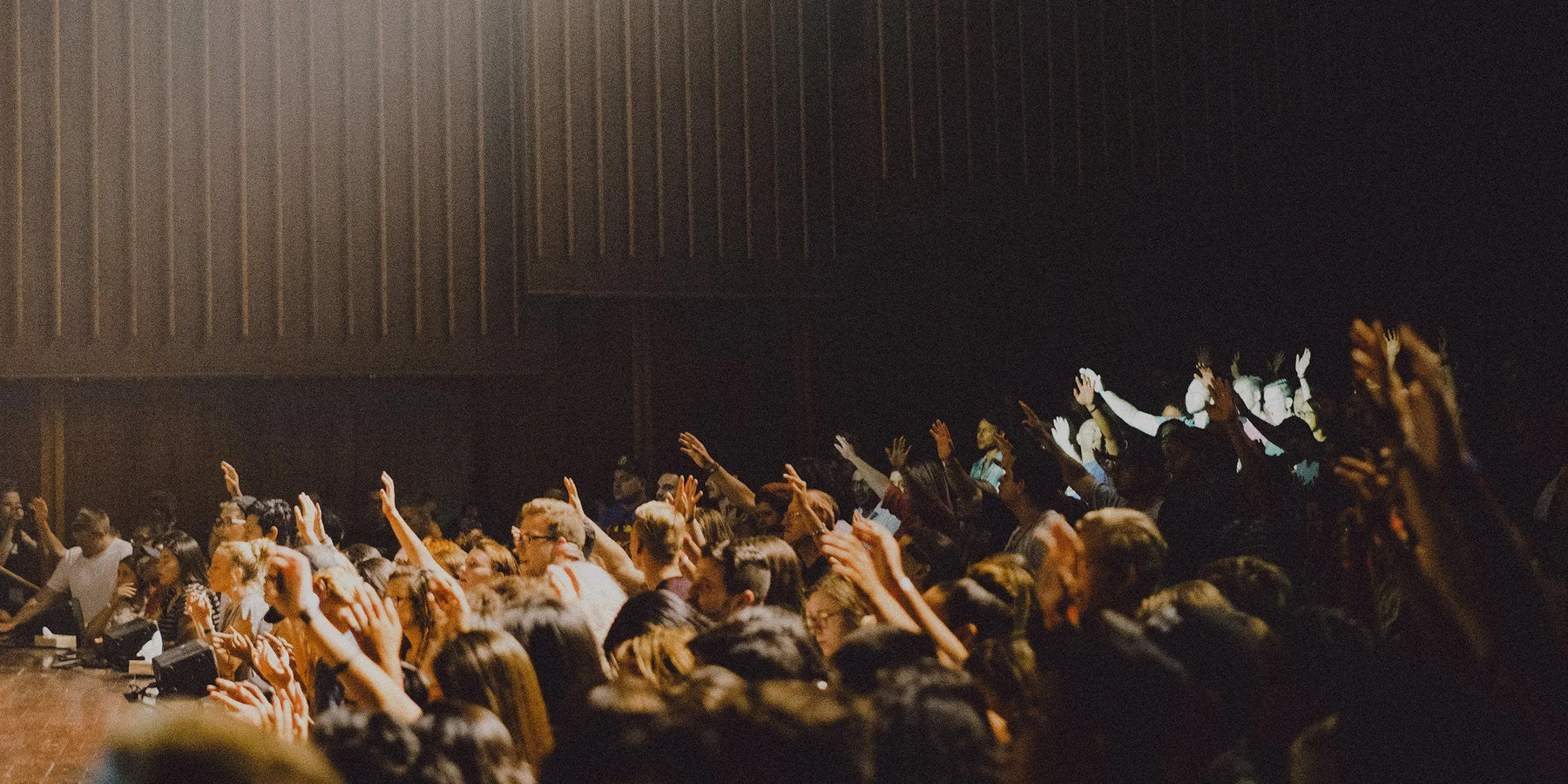 Un auditorium rempli de personnes qui lèvent la main pour prendre la parole.