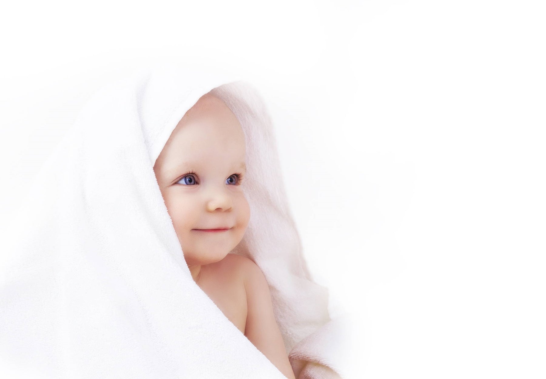 A smiling baby with a white towel on their head