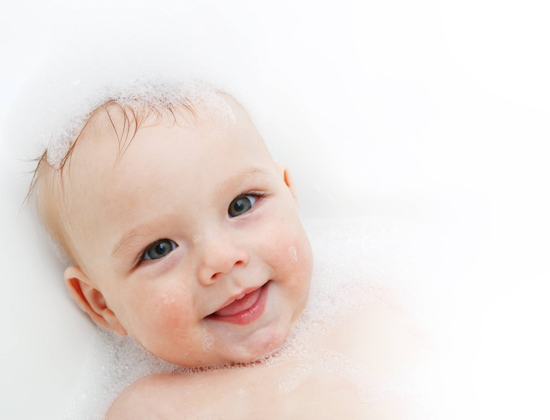 A smiling baby in a bubble bath