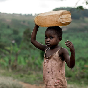 a child walking with a jerrycan of water balanced on their head
