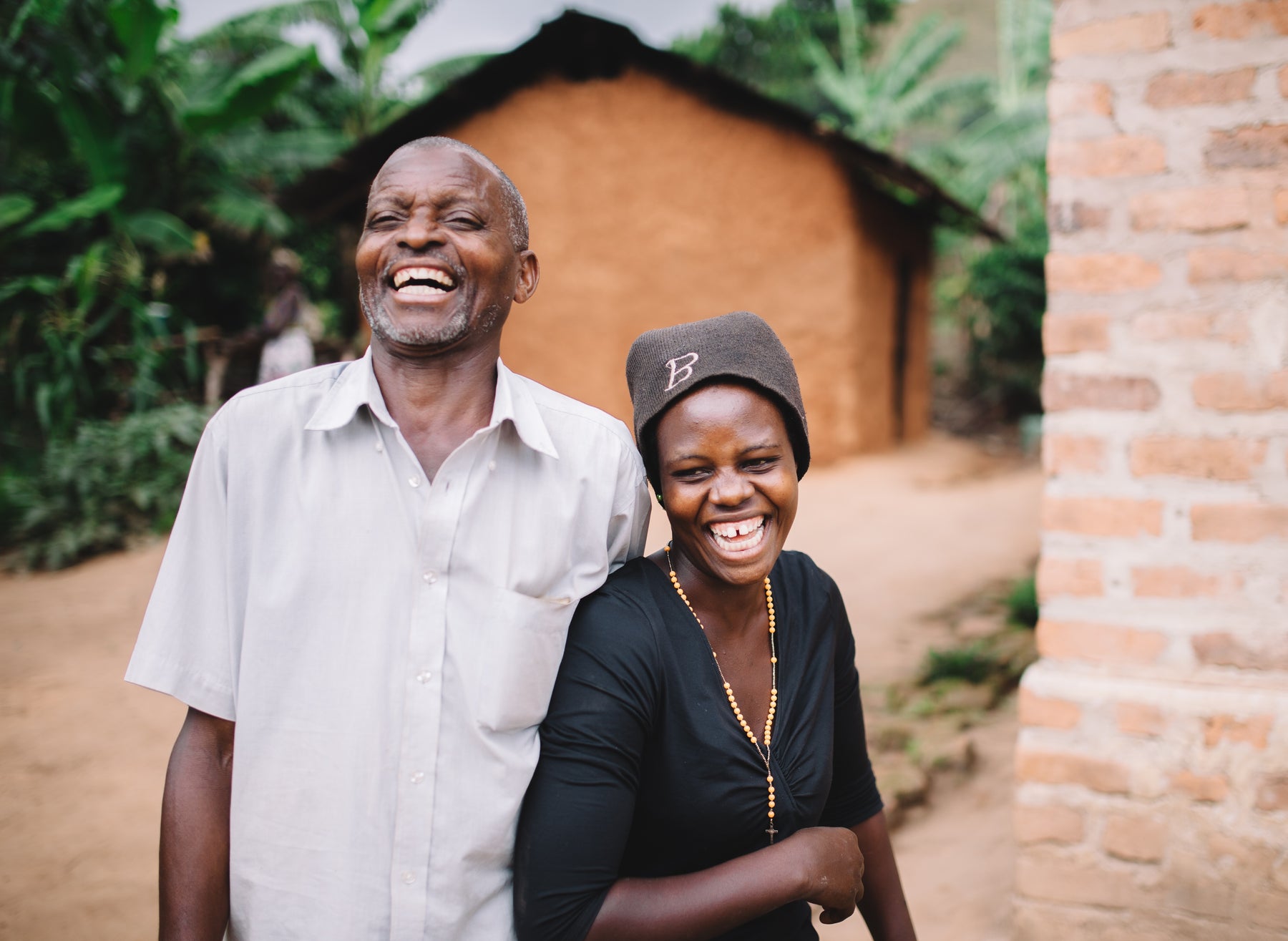 A couple laughing outside of their home in Ghana
